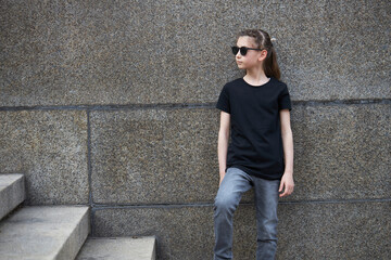 Obraz premium Child girl wearing black t-shirt with space for your logo or mock up outside in an urban area