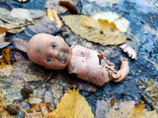Little broken doll forgotten on the street. Symbol of a broken childhood