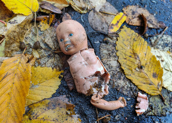 Little broken doll forgotten on the street. Symbol of a broken childhood