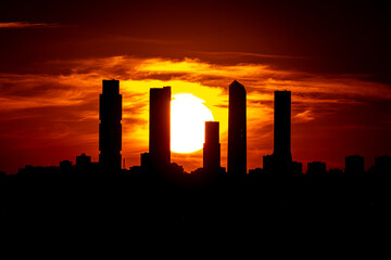 Fototapeta na wymiar Sunset over the silhouette of the five towers of the north castellana of Madrid and the sun.