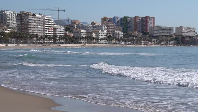 Mediterranean waves breaking on beach Villajoyosa Spain Costa Blanca with apartments in background