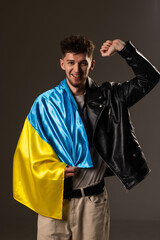 Happy young man with Ukrainian flag on black background