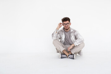 Young man sitting with legs crossed isolated over white background