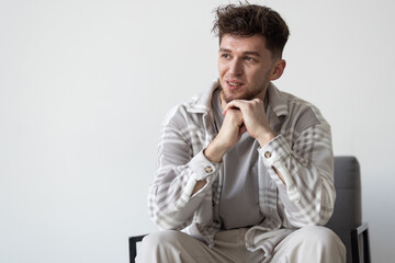 Obraz premium A young handsome man sitting on chairand posing isolated on white background
