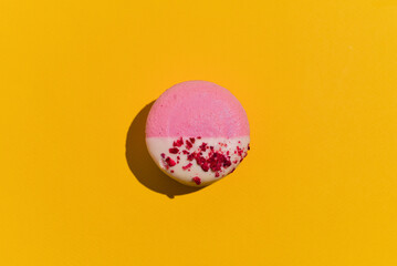 Pink French dessert macaron closeup hard light shot on yellow background