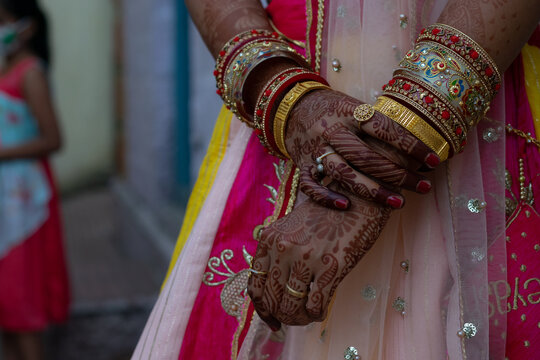 Picture of tattooed(mehndi, henna) hand of an Indian woman or bride along with jewelry such as bangles, rings during festival and marriage, forced, arranged, inter caste, love, dowry, violence, groom.
