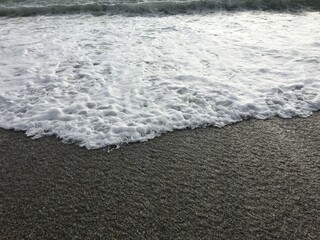 Obraz premium Black Sea coast, sunny day with a view of the blue sky horizon and sea foam waves. Pebbles - round sea stones. Sea stones, pebbles, sea foam, pebbles on the seashore