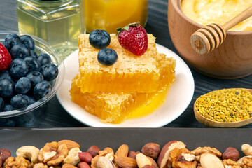 fresh assorted honey, nuts, strawberries and blueberries on a wooden background. healthy organic vitamin food.