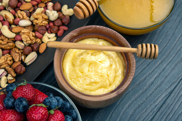 fresh assorted honey, nuts, strawberries and blueberries on a wooden background. healthy organic vitamin food.