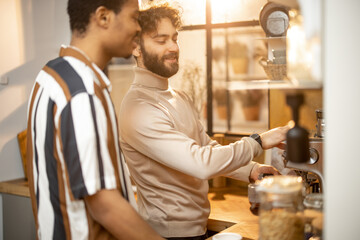 Two guys of different ethnicity having warm conversation while making coffee on kitchen at home. Concept of close male friendship or relationship as gay couple. Caucasian and hispanic man together