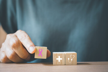 senior woman' hand hold pink ribbon icon on wooden cube block for supporting people living and illness campaign. October Breast Cancer Awareness month,  Healthcare, International Women day