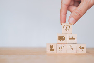 senior's hand arrange health and medical icon on wooden cube blocks, heart and elderly on top, for health insurance, wellness, wellbeing, elderly nursing care concept with copy space