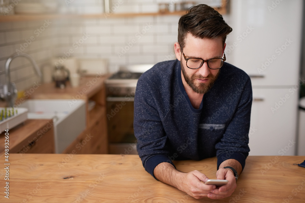 Aufkleber Making plans for his day of leave. Cropped shot of a handsome young man sending a text message while standing in the kitchen at home.