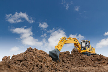 Excavator with bucket lift up  are digging  soil in the construction site on the cloud  and sky   background