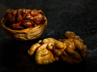 Beautiful textured Half split walnut in a shell and walnut kernel on a black background. Macro close-up, still life, selective focus