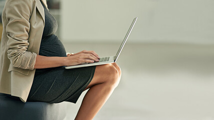 One more email before maternity leave. Cropped shot of a pregnant businesswoman using a laptop in an office.
