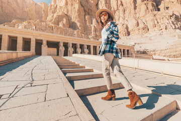 Happy woman traveler explores the ruins of the ancient Egyptian Hatshepsut temple in the heritage city of Luxor. Wonders of the World and tourist experience