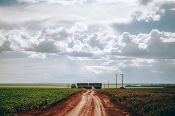 dirt road with a truck and clouded sky
