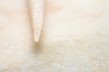 Extreme closeup of biege handmade paper with a toothpick