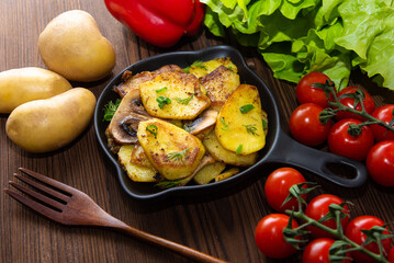 Baked gratin dauphine at home on a wooden table with cherry tomatoes.