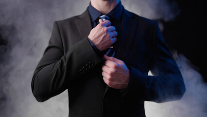 Headless businessman on black background with smoke hold to tie pose