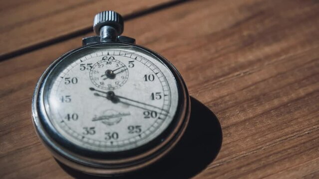 Antique stopwatch lies on wooden table and counts the seconds, timelapse. Old vintage stop watch with moving second hand. Retro chrome chronometer counts time. Dial stopwatch, clock arrow rotates.