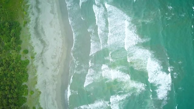 Aerial shot of angry waves crashing to the shore.
