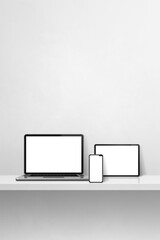 Laptop, mobile phone and digital tablet pc on white concrete wall shelf. Vertical background