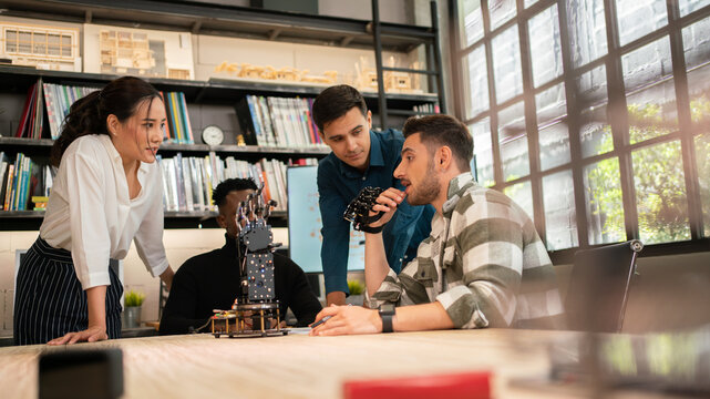New generation designers working on designing new innovations in robotics, thinking new ideas in the office and presenting them to colleagues.