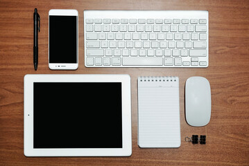 Mix of office supplies and gadgets on a wooden table background. View from above