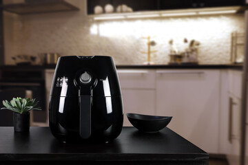 a black deep fryer or oil free fryer , air fryer appliance, is on wooden black table in nice...