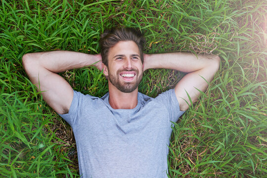 The grass is greener on the other side. High angle shot of a young man lying down on the grass with his hands behind his head.