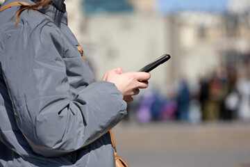 Female hands with smartphone close up on blurred people background. Girl using mobile phone on a...