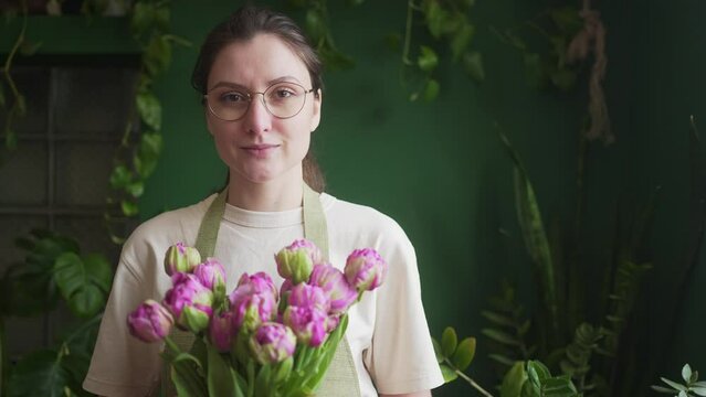 Successful young woman - small business owner. Professional florist with a beautiful bouquet of fresh flowers in the store looks into the camera
