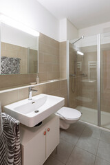 Bathroom with light tiles, sink, toilet and shower