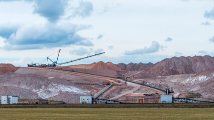Giant spreader or absetzer machinery. A large dumper on a landfill with potash ore. Extracting...