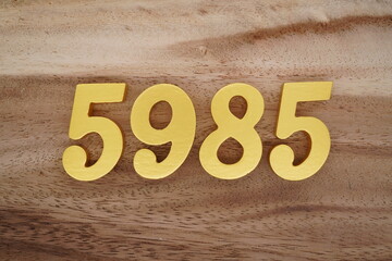 Golden Arabic numerals on a real brown and white wooden floor number 5985