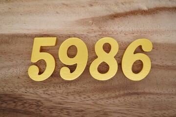 Golden Arabic numerals on a real brown and white wooden floor number 5986