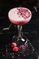Classic pink cocktail garnished with dried flowers and raspberries.