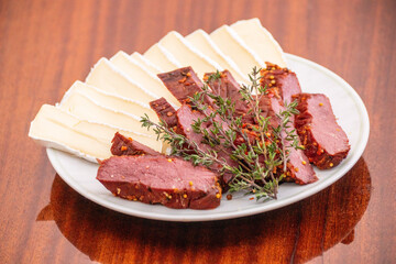 serving plate with sliced meat and cheese and herbs