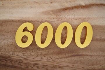 Golden Arabic numerals on a real brown and white wooden floor number 6000
