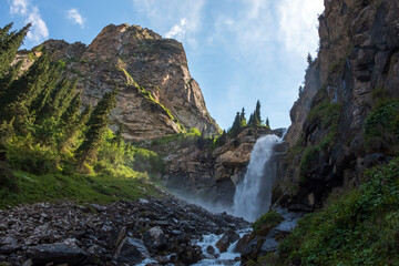 Beautiful waterfall in mountains with. Barskoon waterfall - splashes of Champaign. Travel, tourism in Kyrgyzstan concept.