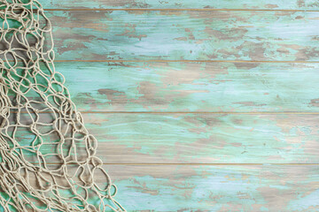 Fishing net on old cyan board background with copy space - obrazy, fototapety, plakaty