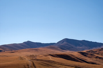 Beautiful mountains with dried orange grass and road going up in autumn season. Natural background. Assy plateau in Ili-Alatau national park.