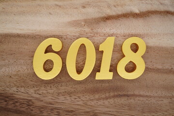 Golden Arabic numerals on a real brown and white wooden floor number 6018