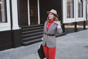 Stylish business woman in jacket and felt hat walks on the city street