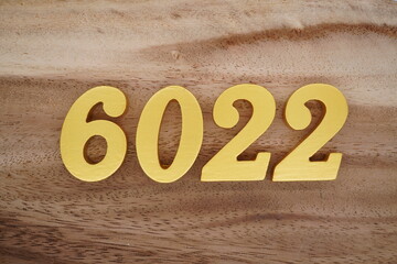 Golden Arabic numerals on a real brown and white wooden floor number 6022