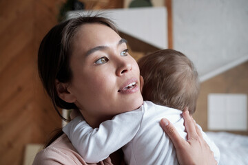 Close-up portrait of beautiful young loving mother holding her baby, cradling her and singing song