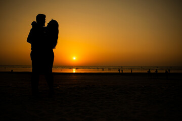 A beautiful silhouette of a couple hugging each other, enjoying intimacy and making love at a beach during sunset.