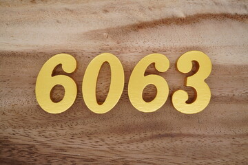 Golden Arabic numerals on a real brown and white wooden floor number 6063